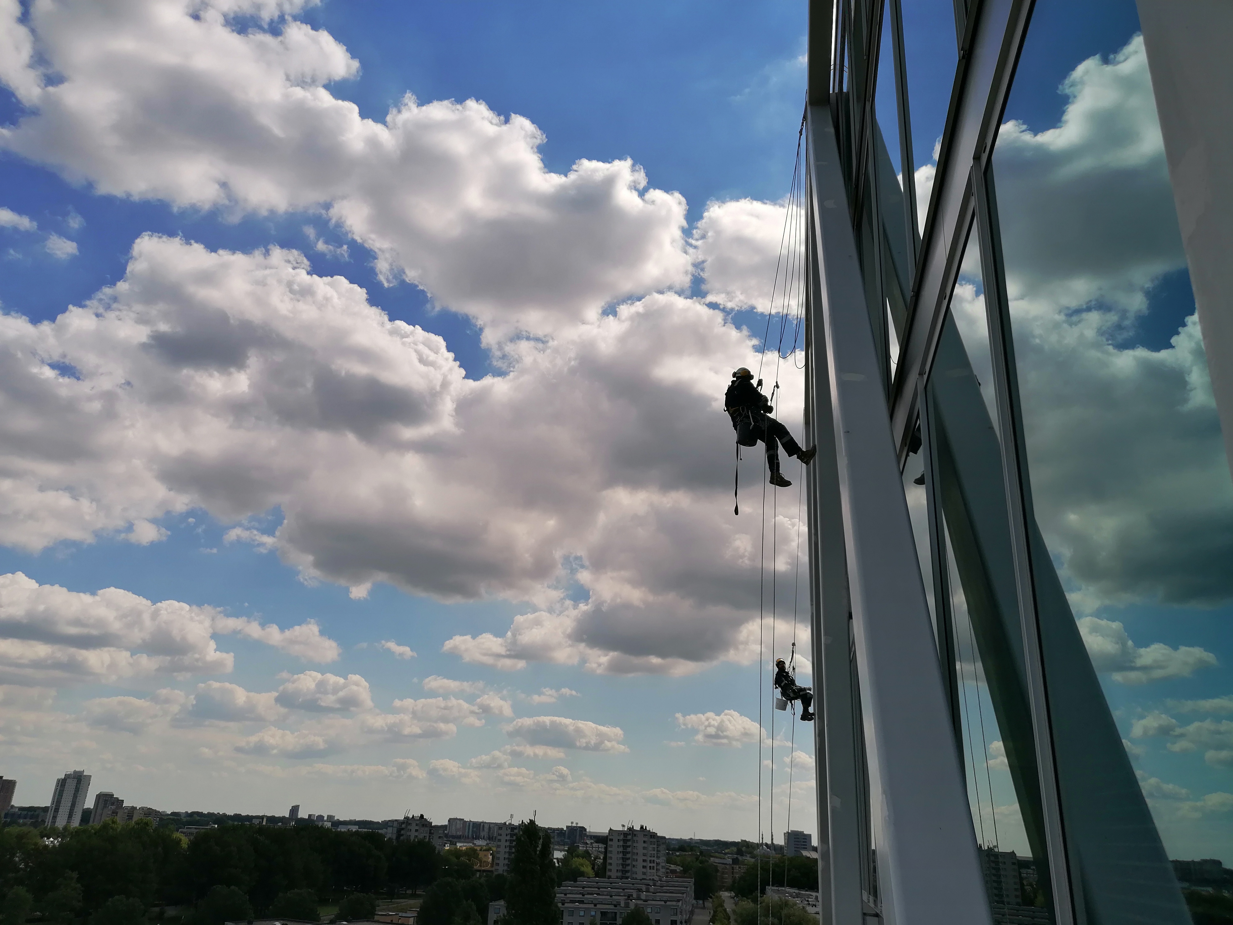 Rope access technicians cleaning windows on a glass building facade